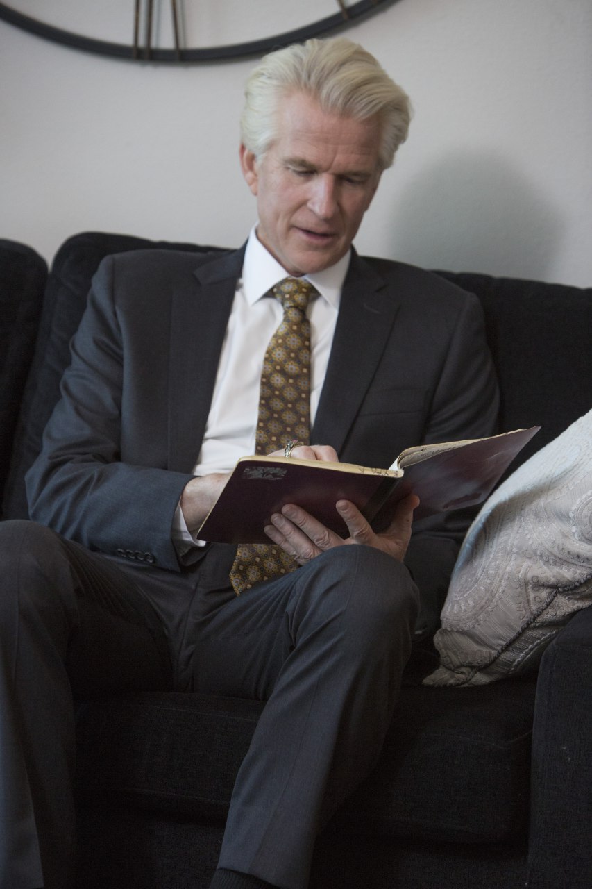 Michael Trainer (Matthew Modine), a high-powered corporate lawyer, sits on a couch and reads from a notebook in 'Foster Boy'.